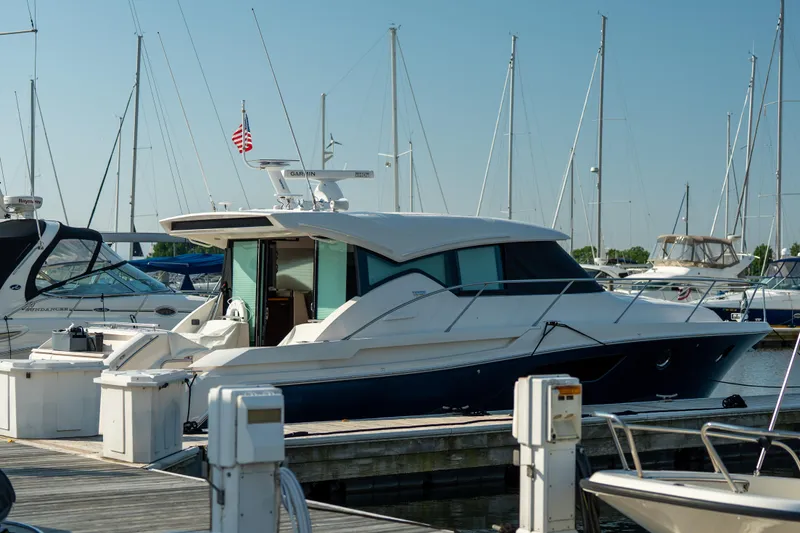 Escapade Yacht Photos Pics 2017 Tiara Yachts C44 Coupe docked at marina with sailboats in background.