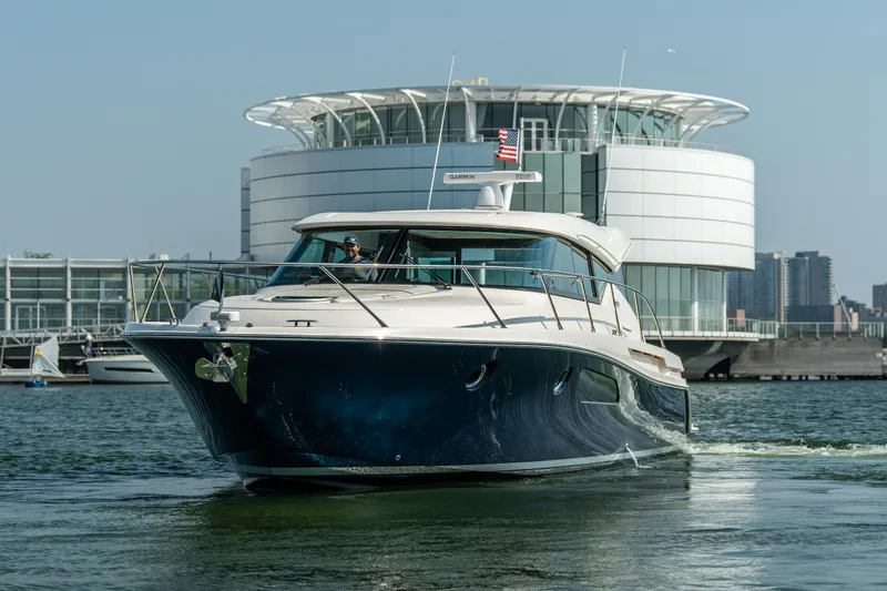 Escapade Yacht Photos Pics 2017 Tiara Yachts C44 Coupe cruising near modern waterfront architecture.