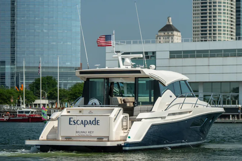Escapade Yacht Photos Pics 2017 Tiara Yachts C44 Coupe cruising near city buildings, American flag flying.