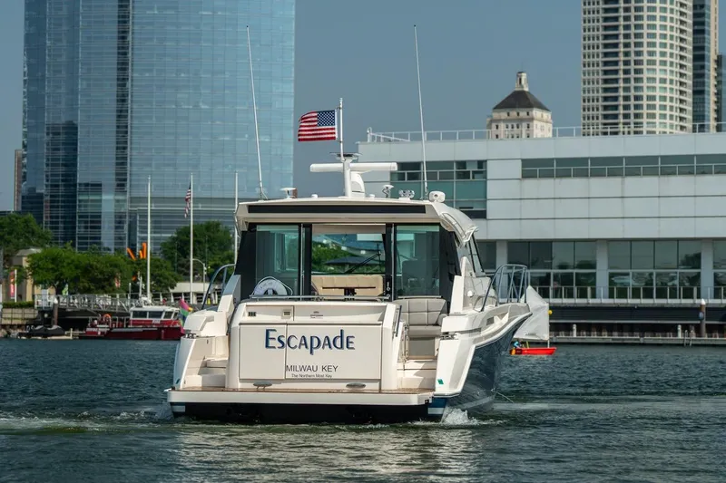 Escapade Yacht Photos Pics 2017 Tiara Yachts C44 Coupe on water, city skyline background.