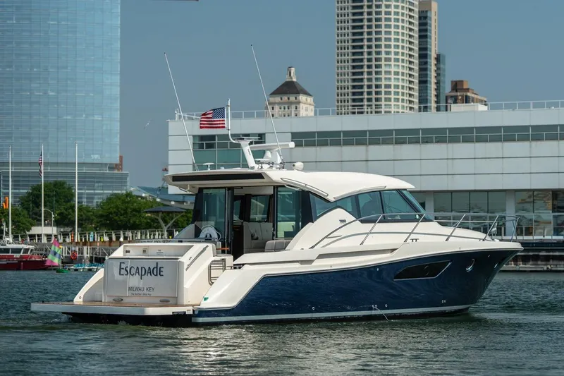 Escapade Yacht Photos Pics 2017 Tiara Yachts C44 Coupe cruising near urban waterfront with skyscrapers in background.