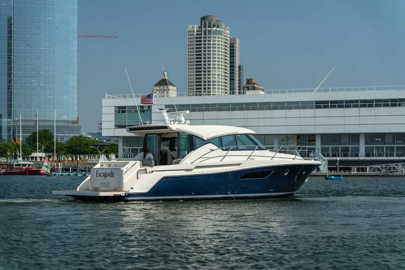 Escapade Yacht Photos Pics 2017 Tiara Yachts C44 Coupe cruising near city waterfront buildings.