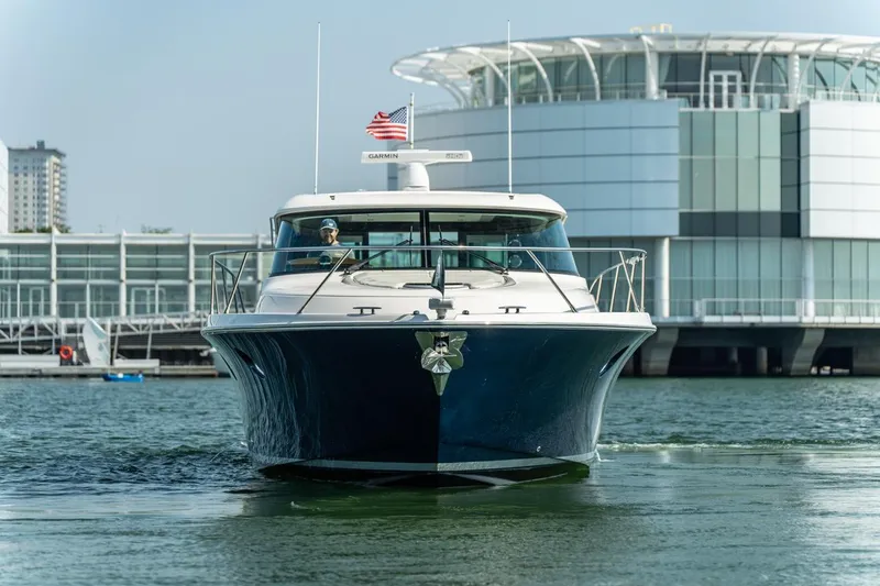 Escapade Yacht Photos Pics 2017 Tiara Yachts C44 Coupe cruising near modern waterfront building.