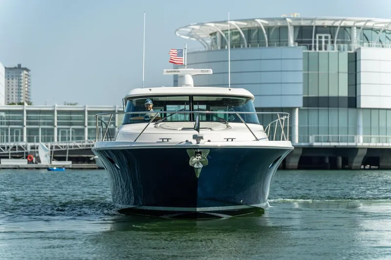 Escapade Yacht Photos Pics 2017 Tiara Yachts C44 Coupe cruising near modern waterfront architecture.