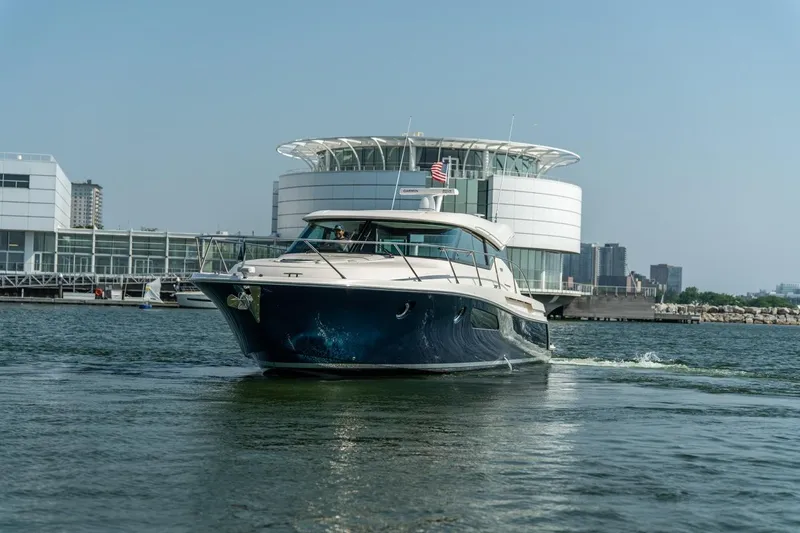 Escapade Yacht Photos Pics 2017 Tiara Yachts C44 Coupe cruising near modern waterfront architecture.