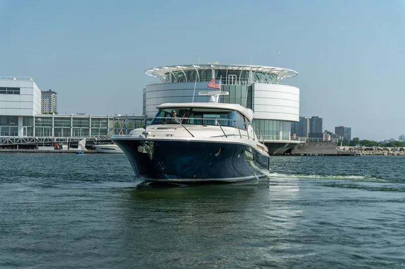 Escapade Yacht Photos Pics 2017 Tiara Yachts C44 Coupe cruising near modern waterfront architecture.