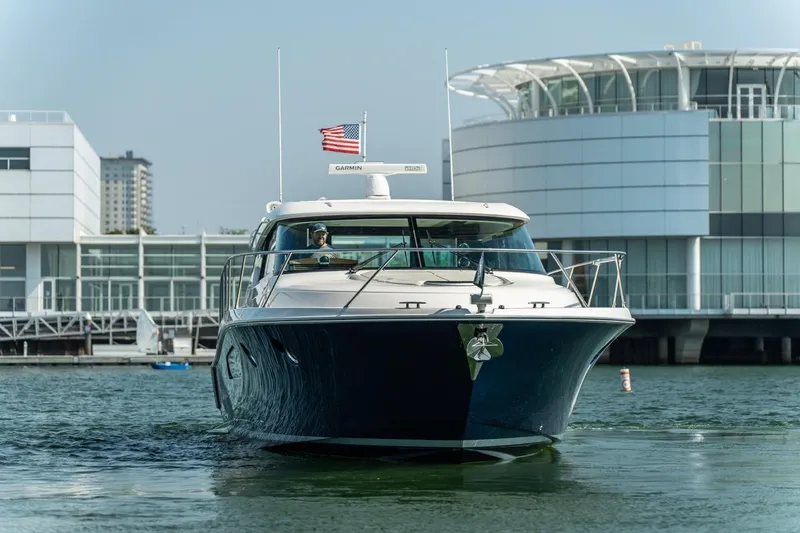 Escapade Yacht Photos Pics 2017 Tiara Yachts C44 Coupe cruising near modern waterfront buildings.