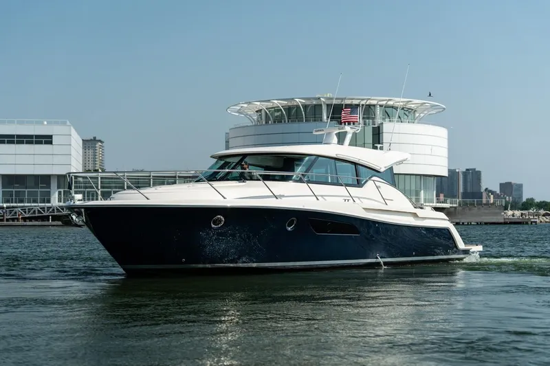 Escapade Yacht Photos Pics 2017 Tiara Yachts C44 Coupe cruising near modern waterfront buildings.