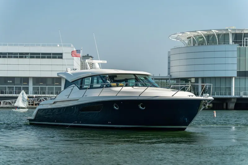 Escapade Yacht Photos Pics 2017 Tiara Yachts C44 Coupe in marina, sleek design, modern architecture backdrop.