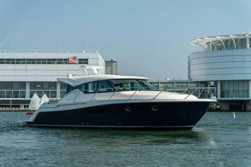 Escapade Yacht Photos Pics 2017 Tiara Yachts C44 Coupe in marina, modern architecture background.