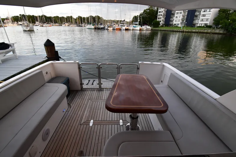Promesa Yacht Photos Pics Luxury Hylas M44 yacht deck with seating and table, overlooking marina.