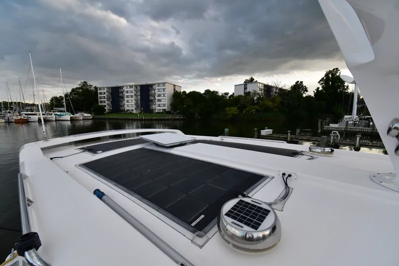 Promesa Yacht Photos Pics Hylas M44 yacht with solar panels docked near waterfront buildings, cloudy sky.