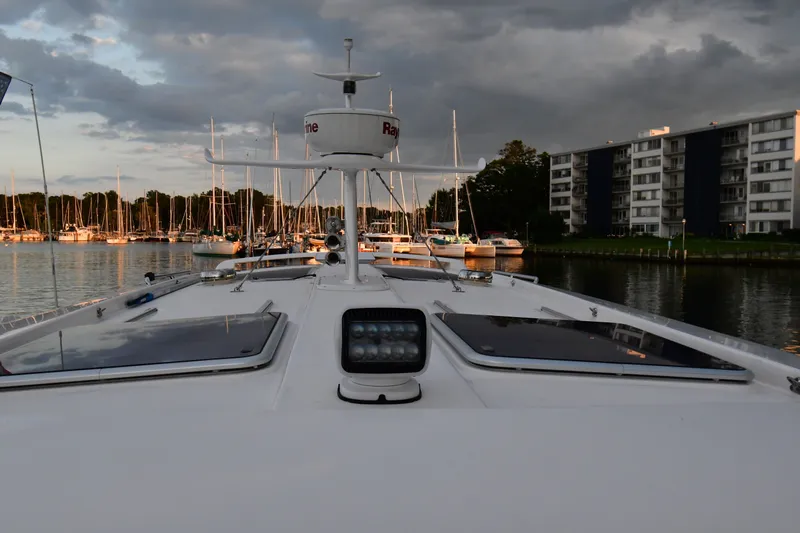 Promesa Yacht Photos Pics Bow view of 2021 Hylas M44 yacht in marina, with cloudy sky and waterfront buildings.