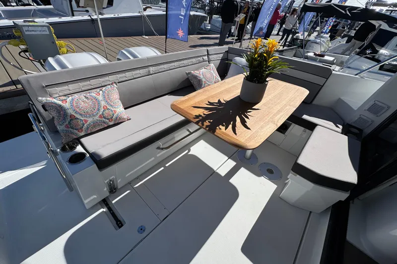  Yacht Photos Pics 2026 Jeanneau NC 1095 boat interior with seating, table, and decorative pillows.