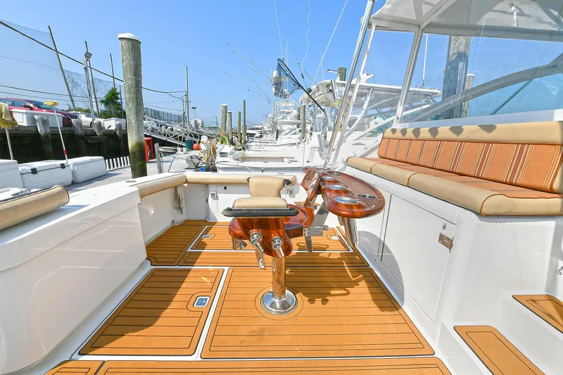  Yacht Photos Pics 1999 Cabo 45 Express yacht with teak deck and fishing chair, docked at marina.