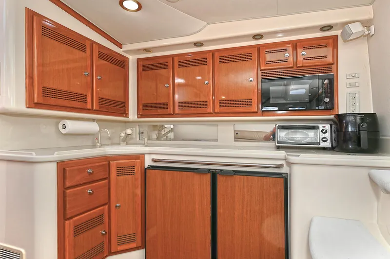  Yacht Photos Pics 1999 Cabo 45 Express yacht kitchen with wooden cabinets, microwave, and appliances.