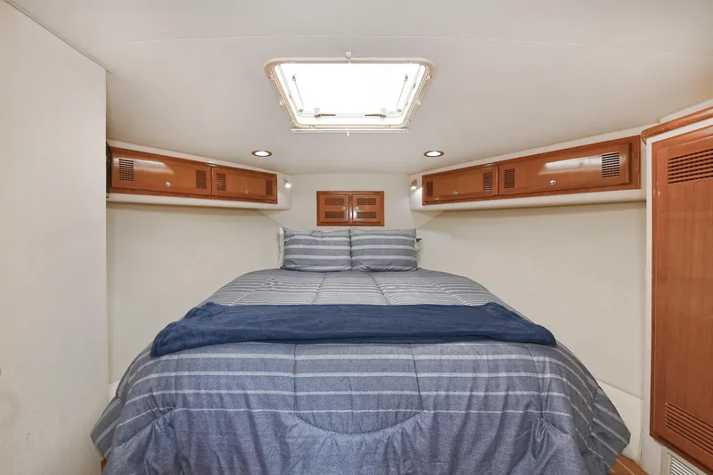  Yacht Photos Pics Cozy cabin interior of 1999 Cabo 45 Express with striped bedding and wooden storage.