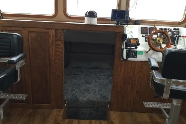 Horus Yacht Photos Pics Pilothouse interior of 2013 Custom Trawler 45 with wood paneling and navigation equipment.