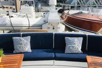 Luxurious yacht deck with striped cushions, wooden tables, and docked boats in the background.