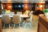 Luxurious yacht interior with elegant dining area, plush chairs, and large TV, 1966 Custom Global Engineering.