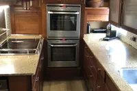 Modern kitchen with double ovens, granite countertops, and wooden cabinetry, featuring a 1966 Custom Global Engineering design.