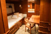 Luxurious wooden cabin interior with bed, desk, and chair on a 1966 Custom GLOBAL ENGINEERING model.