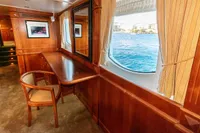 Luxurious yacht interior with wooden furnishings, large window, and ocean view, Custom GLOBAL ENGINEERING 1966.