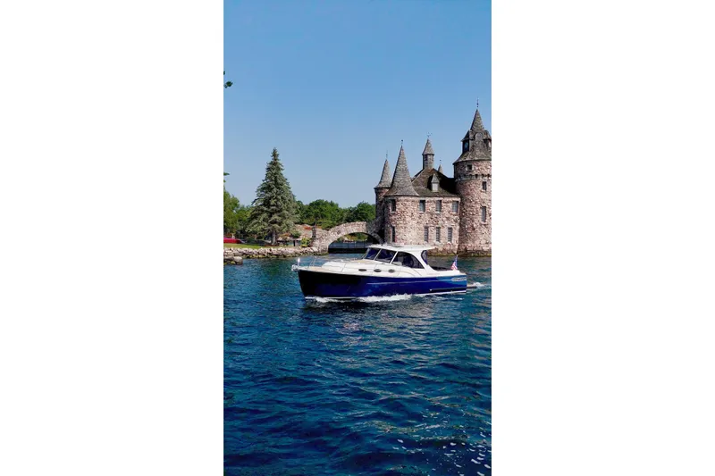  Yacht Photos Pics 2024 DaVinci 30HT boat cruising near a historic castle on a sunny day.