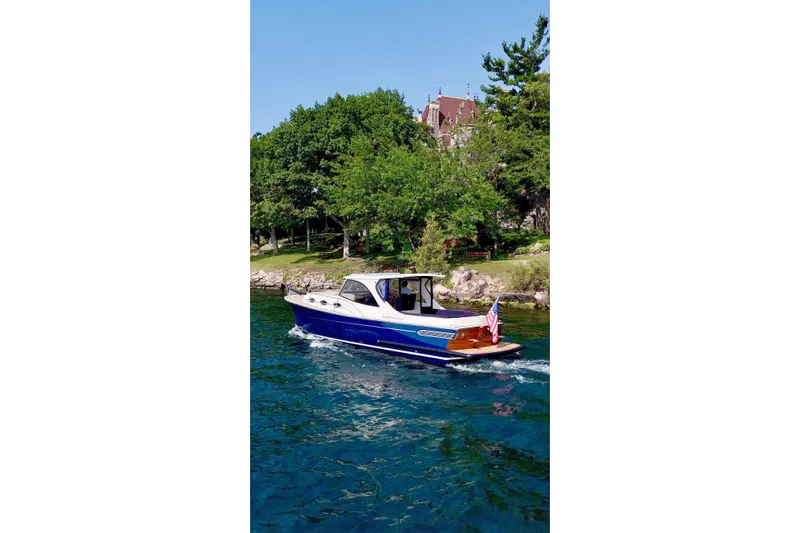  Yacht Photos Pics 2024 DaVinci 30HT boat cruising on a scenic lake with lush greenery.