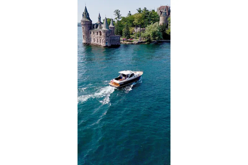  Yacht Photos Pics 2024 DaVinci 30HT boat cruising near a historic castle on a serene lake.