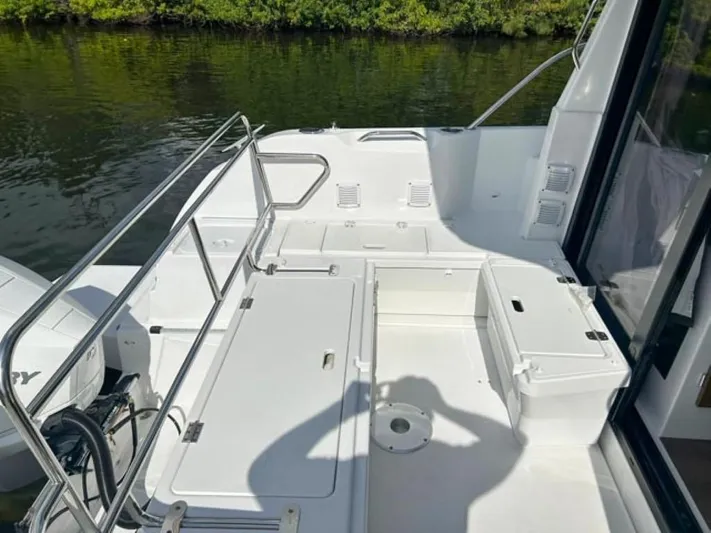  Yacht Photos Pics 2025 Beneteau Antares 9 boat deck with seating and storage, near water.