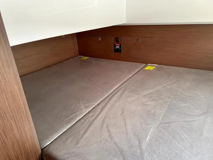  Yacht Photos Pics 2025 Beneteau Antares 9 cabin interior with wooden finish and cushioned bedding.