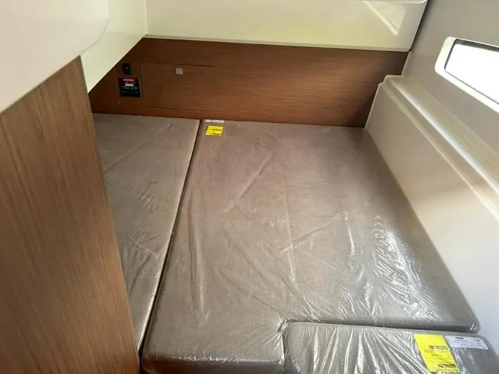  Yacht Photos Pics 2025 Beneteau Antares 9 cabin interior with cushioned bed and wooden paneling.