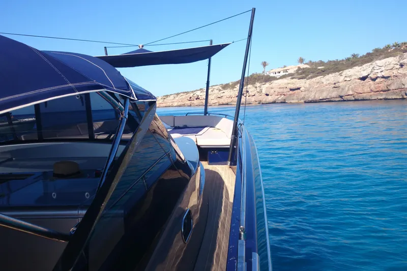 Double K Yacht Photos Pics CNM Continental Tender 50 yacht cruising near rocky coastline, clear blue water, sunny day.