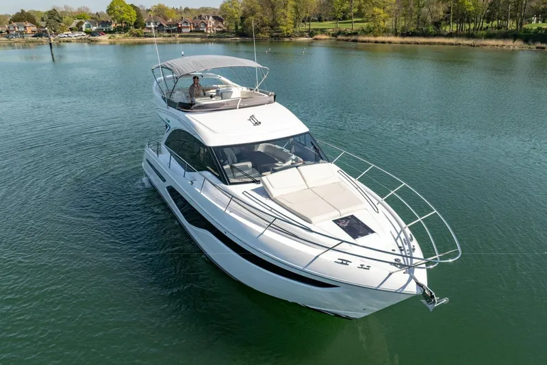  Yacht Photos Pics 2025 Princess F50 yacht cruising on a serene lake with lush greenery.