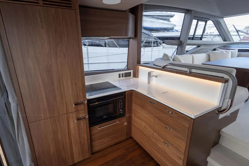  Yacht Photos Pics Luxurious 2025 Princess F50 yacht interior kitchen with modern wood cabinetry and sleek design.