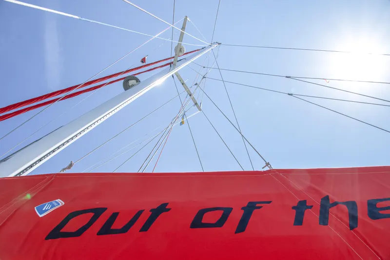 Out Of The Woods Yacht Photos Pics Red sail of NEEL 51 trimaran, 2022, under blue sky.
