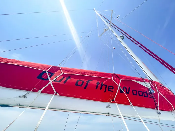 Out Of The Woods Yacht Photos Pics Red sailboat with 'Out of the Woods' text, blue sky.