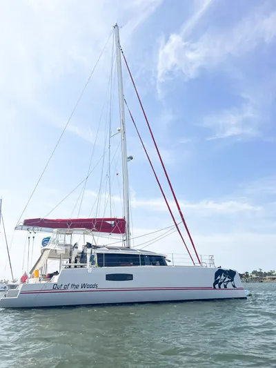 Out Of The Woods Yacht Photos Pics NEEL 51 Trimaran 2022 on calm water with blue sky.