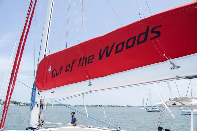 Out Of The Woods Yacht Photos Pics NEEL 51 sailboat with red sail, 'Out of the Woods' inscription.