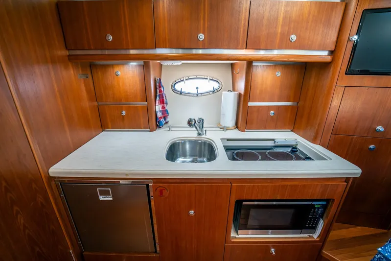 Maggie Yacht Photos Pics 2005 Tiara Yachts 3200 Open galley with wood cabinetry, sink, stove, and microwave.