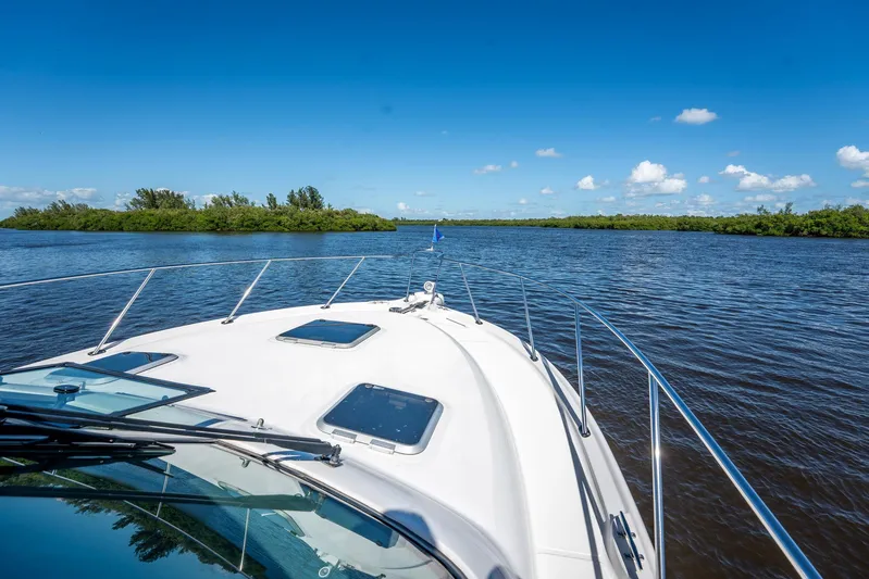 Maggie Yacht Photos Pics 2005 Tiara Yachts 3200 Open cruising on a serene river under a clear blue sky.
