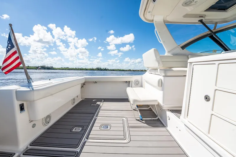 Maggie Yacht Photos Pics 2005 Tiara Yachts 3200 Open boat deck with American flag, under clear blue sky.