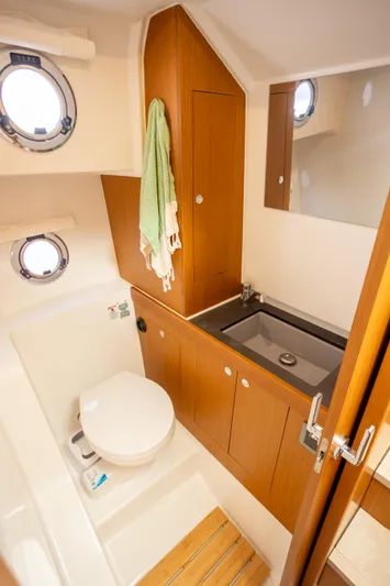 Everything Is Fine Yacht Photos Pics 2019 Beneteau Swift Trawler 30 bathroom with wood cabinetry, sink, and porthole windows.