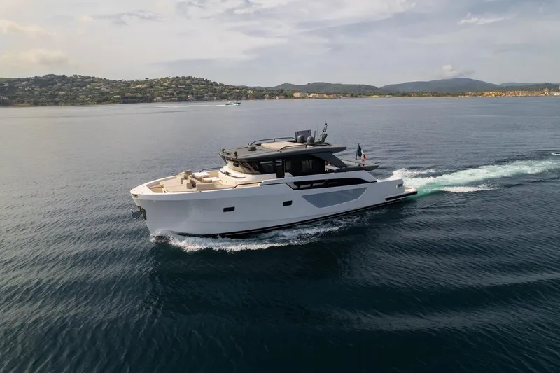  Yacht Photos Pics 2025 Bluegame BGX 63 yacht cruising on calm waters near a scenic coastline.