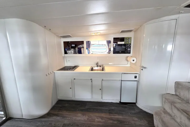 Halcyon Yacht Photos Pics Interior of 1984 MAGNUM MARINE 53 yacht kitchen with modern appliances and white cabinetry.