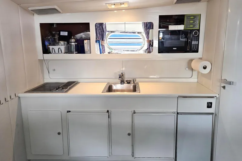 Halcyon Yacht Photos Pics Compact kitchen in a 1984 MAGNUM MARINE 53 yacht, featuring sink, stove, and microwave.