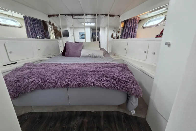 Halcyon Yacht Photos Pics Interior of 1984 MAGNUM MARINE 53 yacht with cozy bed and purple accents.