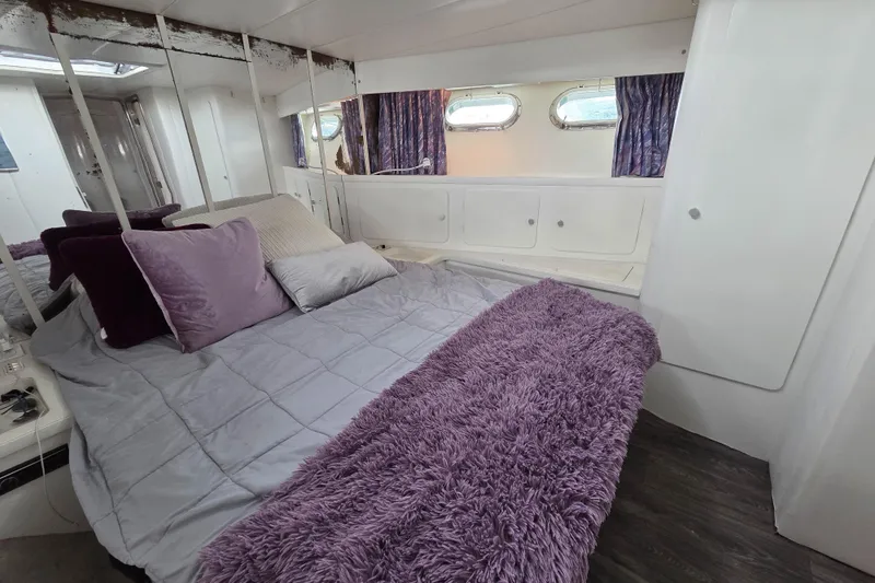 Halcyon Yacht Photos Pics Cozy bedroom in 1984 MAGNUM MARINE 53 yacht with plush bedding and porthole windows.
