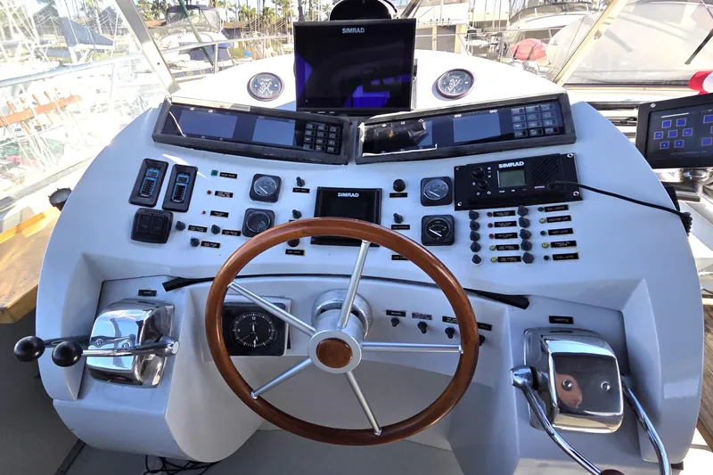 Halcyon Yacht Photos Pics Control panel of a 1984 Magnum Marine 53 yacht with wooden steering wheel and navigation instruments.